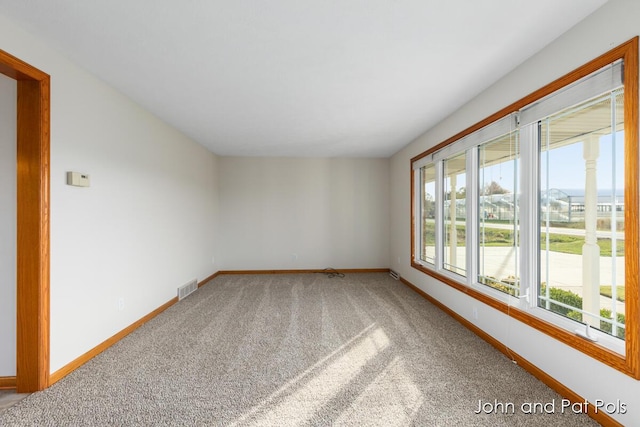 carpeted spare room featuring visible vents and baseboards