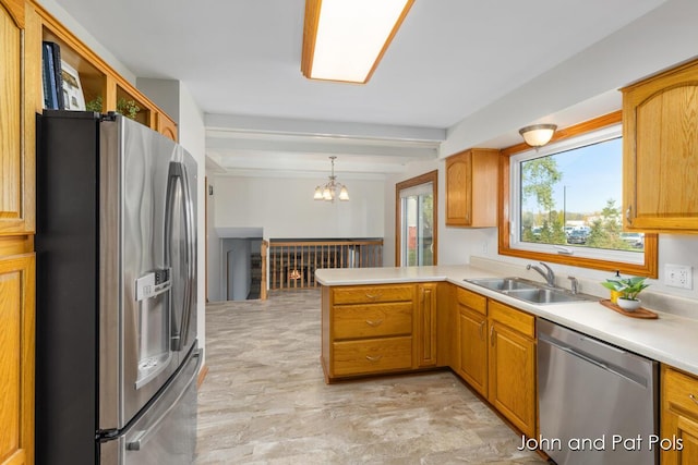 kitchen featuring beam ceiling, light countertops, appliances with stainless steel finishes, a sink, and a peninsula