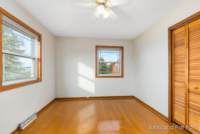 unfurnished bedroom featuring baseboards, visible vents, ceiling fan, light wood-style floors, and a closet