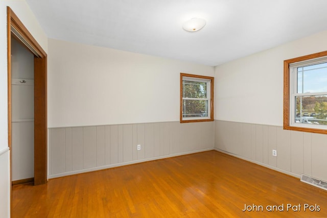 spare room featuring wainscoting, wood finished floors, and visible vents