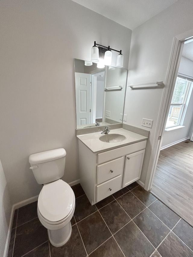 bathroom featuring toilet, tile patterned floors, baseboards, and vanity