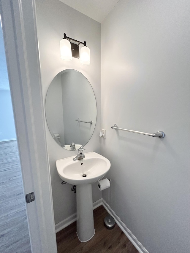 bathroom with a sink, baseboards, and wood finished floors