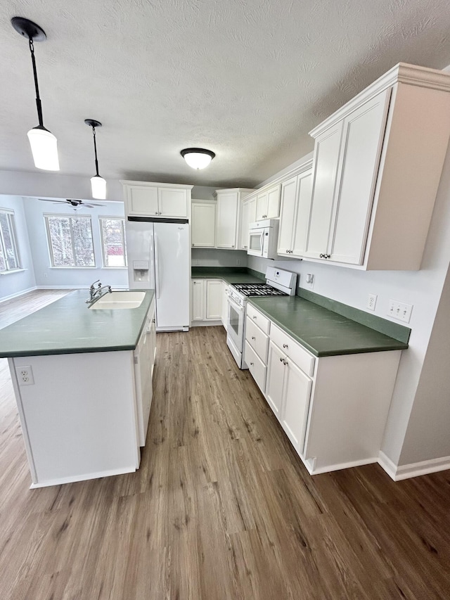 kitchen featuring dark countertops, white appliances, a sink, and wood finished floors