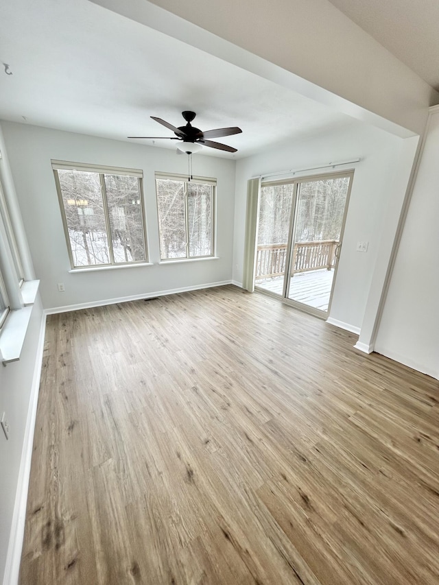 unfurnished living room featuring ceiling fan, baseboards, and wood finished floors