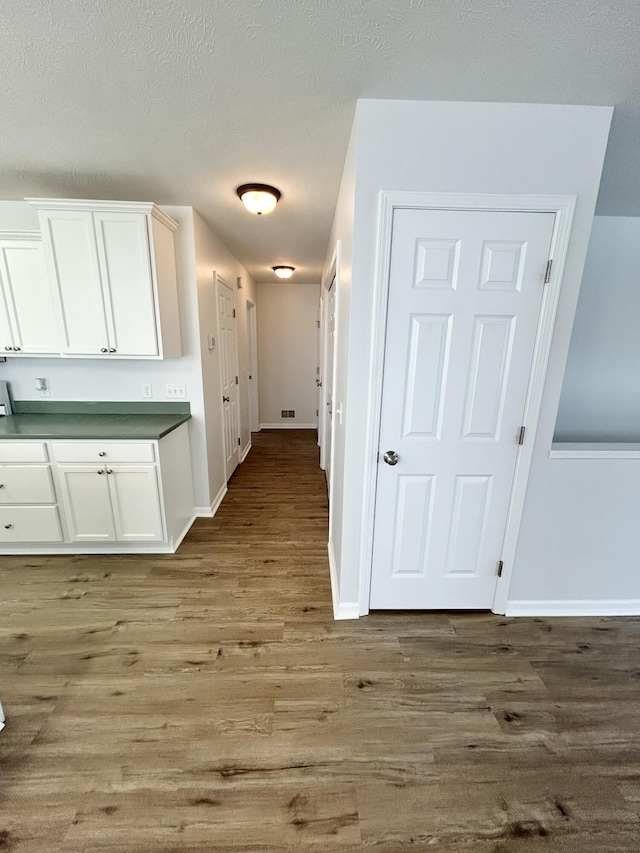 kitchen with baseboards, wood finished floors, and white cabinets