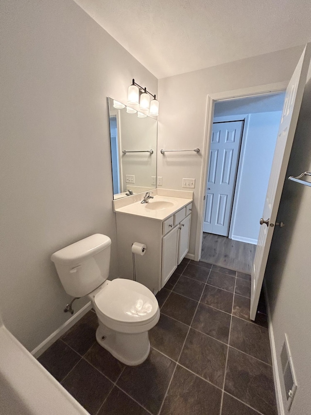 bathroom featuring baseboards, toilet, vanity, and tile patterned floors