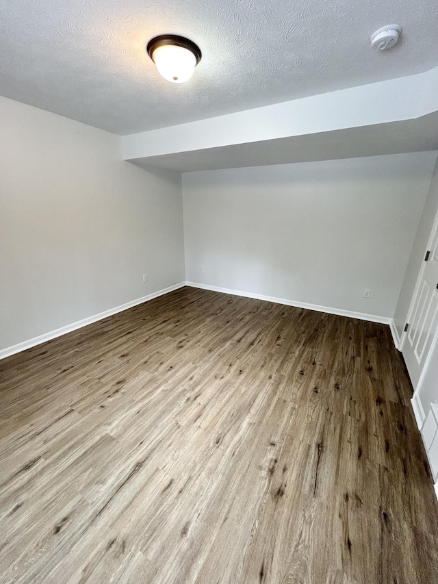 interior space featuring a textured ceiling, baseboards, and wood finished floors