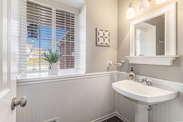 bathroom with a wainscoted wall and a sink