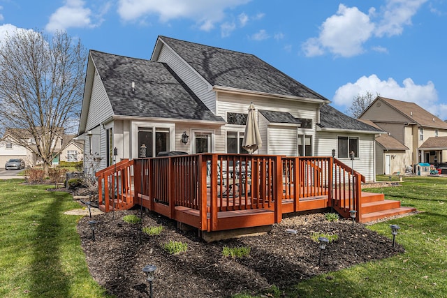 rear view of house with roof with shingles, a deck, and a yard