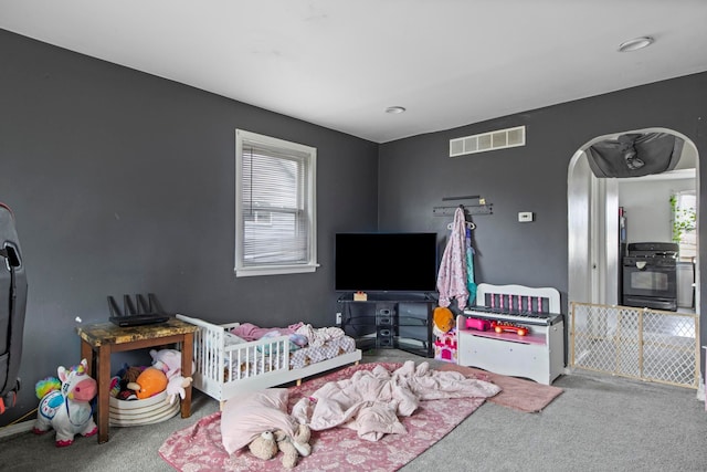 bedroom with carpet, visible vents, and arched walkways