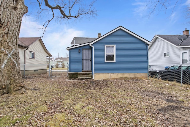 back of property featuring entry steps, a chimney, and fence