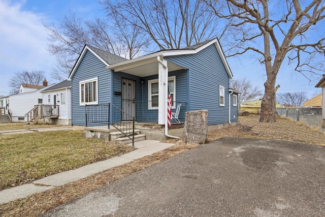 bungalow featuring a porch, a front yard, and a shingled roof