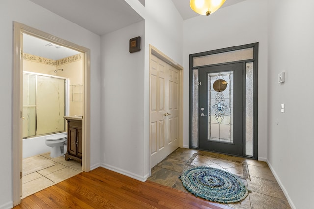 foyer featuring visible vents, baseboards, and wood finished floors