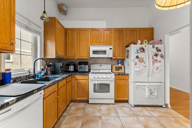 kitchen featuring brown cabinets, backsplash, light tile patterned flooring, a sink, and white appliances