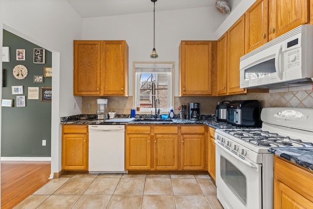 kitchen featuring tasteful backsplash, white appliances, a sink, and light tile patterned floors