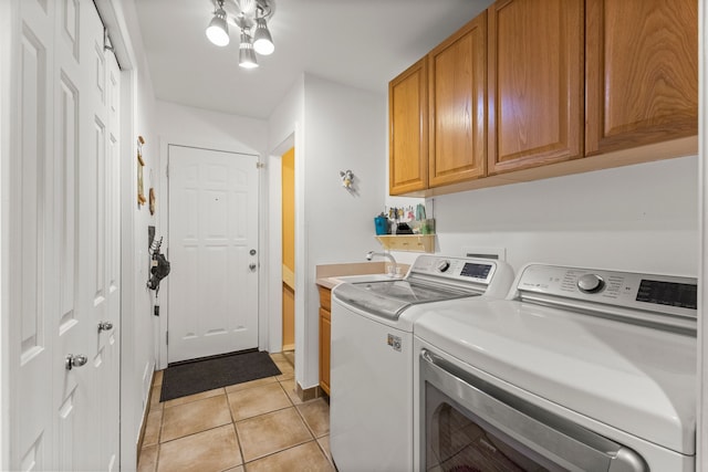 washroom featuring light tile patterned floors, a sink, washing machine and clothes dryer, and cabinet space