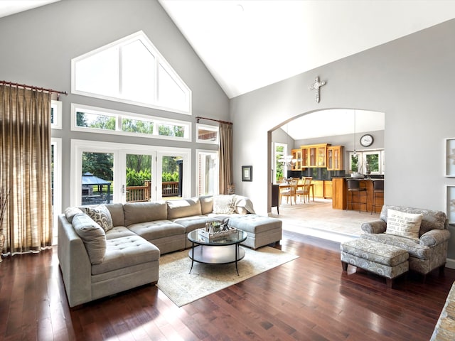 living room featuring arched walkways, high vaulted ceiling, and hardwood / wood-style flooring