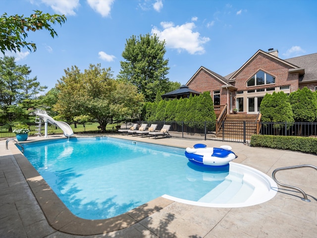 view of swimming pool featuring a fenced in pool, a patio, stairs, fence, and a water slide