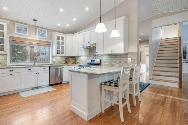 kitchen with appliances with stainless steel finishes, white cabinets, a sink, a peninsula, and under cabinet range hood