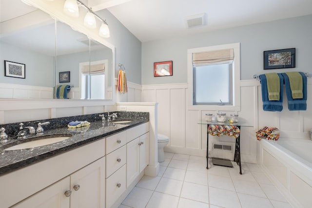 full bath with toilet, a wainscoted wall, visible vents, and a sink