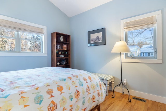 bedroom featuring lofted ceiling, wood finished floors, visible vents, and baseboards