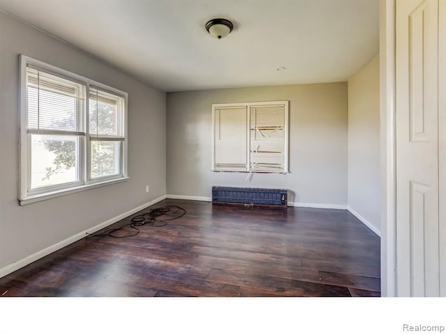 empty room with radiator heating unit, baseboards, and wood finished floors