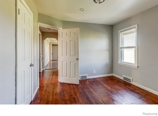 unfurnished bedroom featuring visible vents, baseboards, and wood finished floors