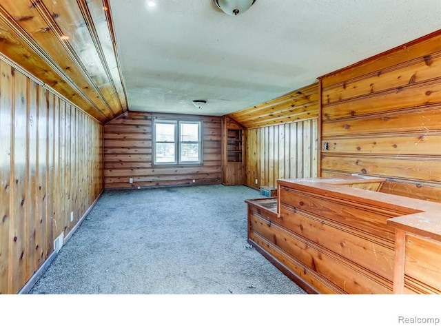 interior space featuring lofted ceiling and wooden walls