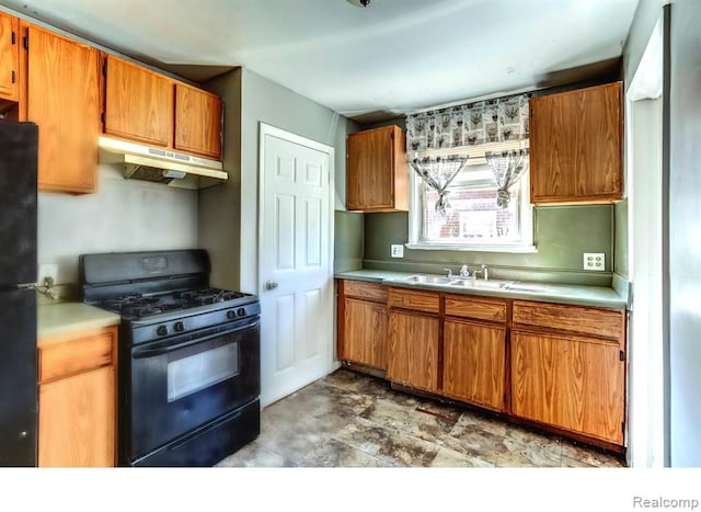 kitchen with light countertops, a sink, under cabinet range hood, and black appliances