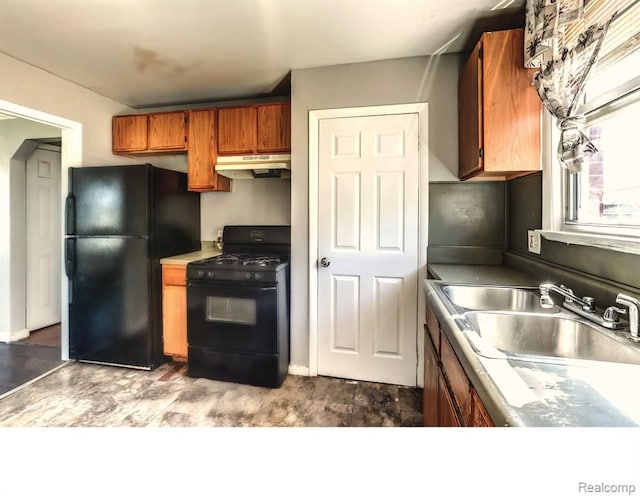 kitchen with under cabinet range hood, a sink, light countertops, brown cabinets, and black appliances