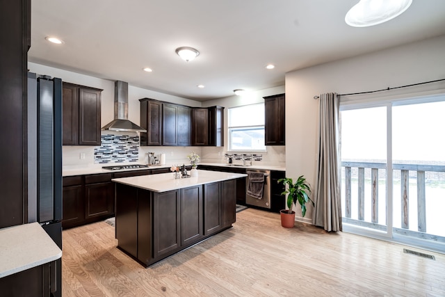 kitchen with appliances with stainless steel finishes, light countertops, visible vents, and wall chimney range hood