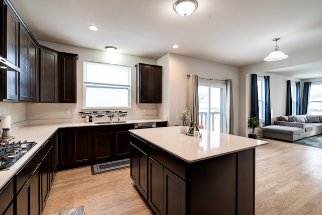 kitchen with light wood-style flooring, open floor plan, light countertops, dark brown cabinets, and stainless steel gas cooktop