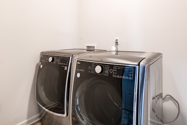 clothes washing area with washing machine and dryer, laundry area, and baseboards