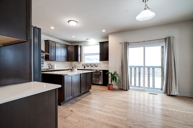 kitchen featuring dark brown cabinets, wall chimney exhaust hood, light countertops, and light wood-style floors