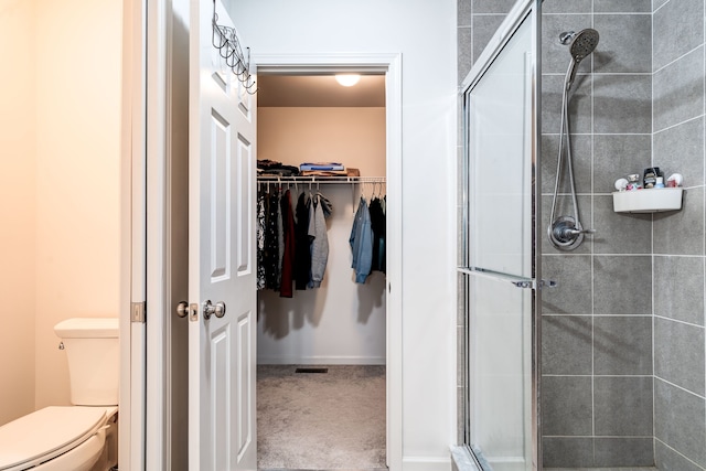 bathroom featuring a stall shower, a spacious closet, and toilet