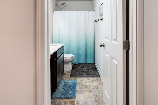 full bathroom with toilet, stone finish floor, a shower with shower curtain, and vanity