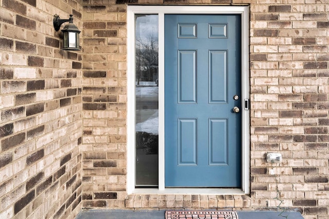 view of exterior entry featuring brick siding