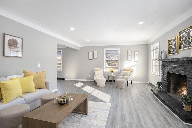 living area with a warm lit fireplace, baseboards, wood finished floors, and recessed lighting