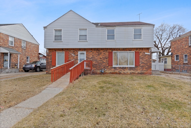 view of front of home with brick siding, a front yard, and fence