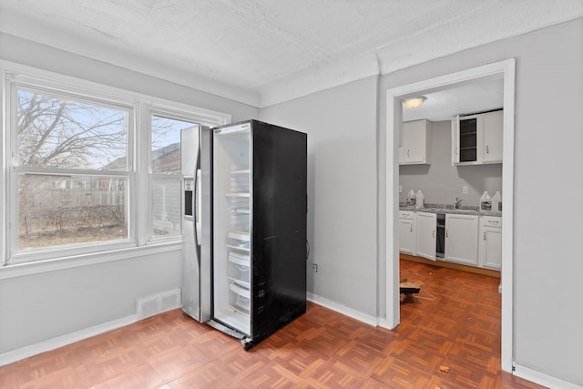 interior space with baseboards, a textured ceiling, visible vents, and a wealth of natural light