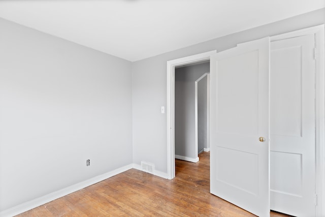 unfurnished bedroom featuring visible vents, light wood-style flooring, and baseboards