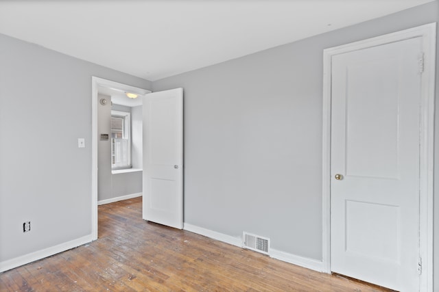 unfurnished room with hardwood / wood-style floors, visible vents, and baseboards