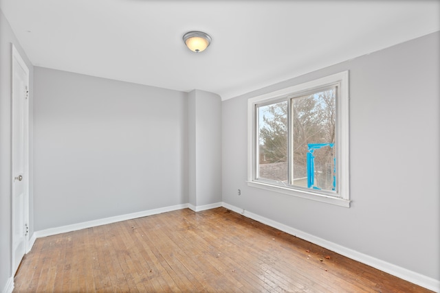 spare room with baseboards and hardwood / wood-style floors