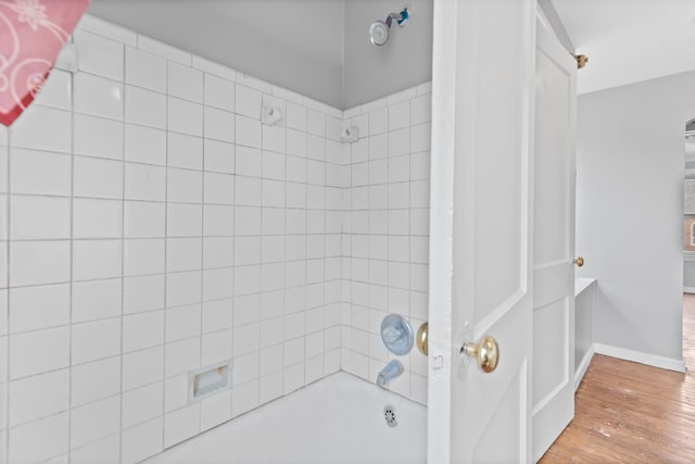 bathroom with baseboards, shower / bathtub combination, and wood finished floors