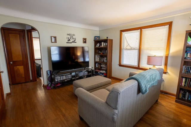 living room with arched walkways, baseboards, and wood finished floors