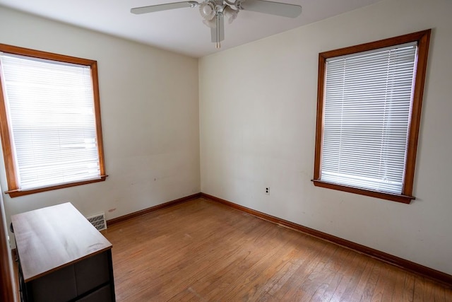 spare room with a healthy amount of sunlight, light wood finished floors, visible vents, and baseboards