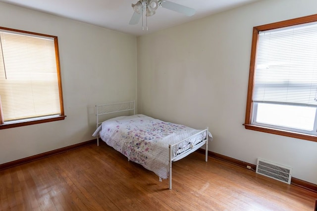 bedroom featuring visible vents, ceiling fan, light wood-style flooring, and baseboards