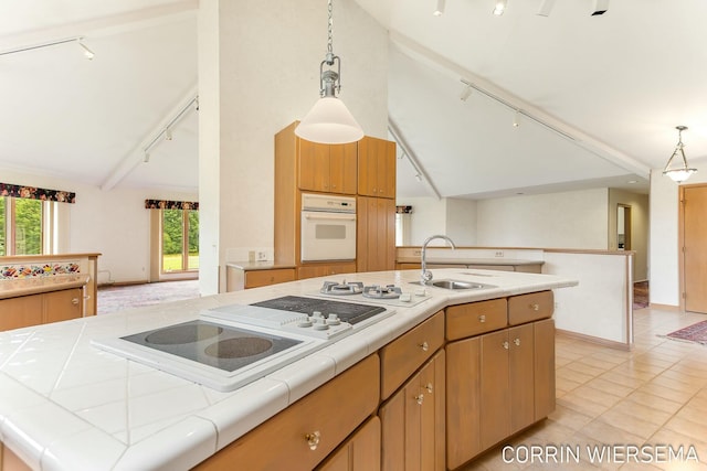 kitchen with tile countertops, white appliances, a healthy amount of sunlight, and a sink