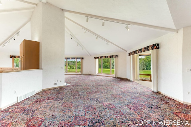 unfurnished living room featuring vaulted ceiling with beams, track lighting, visible vents, and carpet flooring