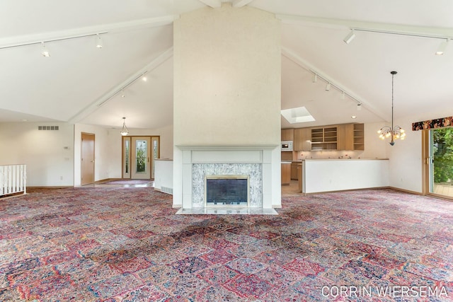 unfurnished living room with a chandelier, carpet floors, a high end fireplace, and track lighting